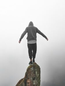 person in gray hoodie standing on rock