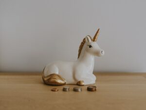 white and gold ceramic unicorn figurine near coins