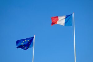 two flags flying next to each other in a blue sky